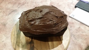 Image Description: a picture of Devil's Food Cake iced and ready to eat on a round wooden chopping board