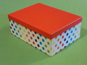 Image Description: a medium sized white box with a rainbow-spectrum of polka-dots decorating the outside with a bright-red lid on top